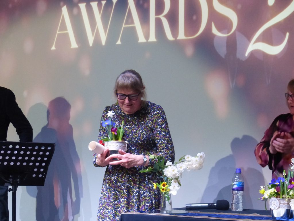 Image of a lady holding flowers as part of her prize 