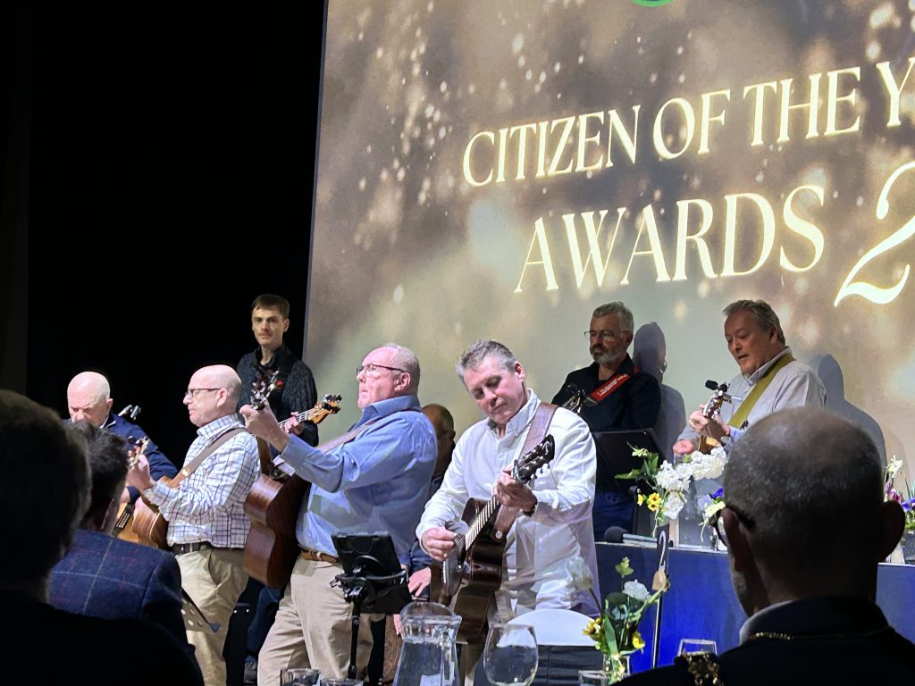 Witney Guitar Club, a group of men with acoustic and electric guitars and a drum box